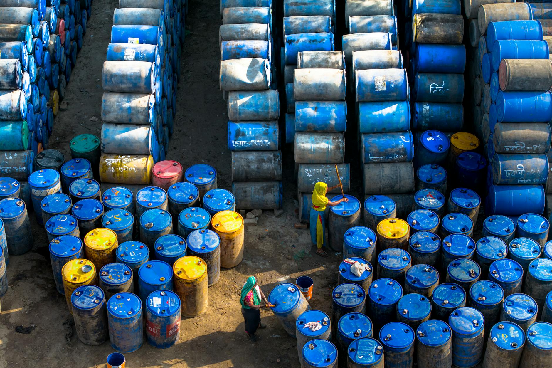 Dwóch pracowników kontroluje niebieskie beczki ADR na zewnątrz