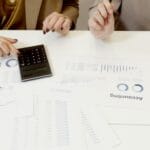 Dwóch specjalistów analizuje dokumenty finansowe przy użyciu kalkulatora