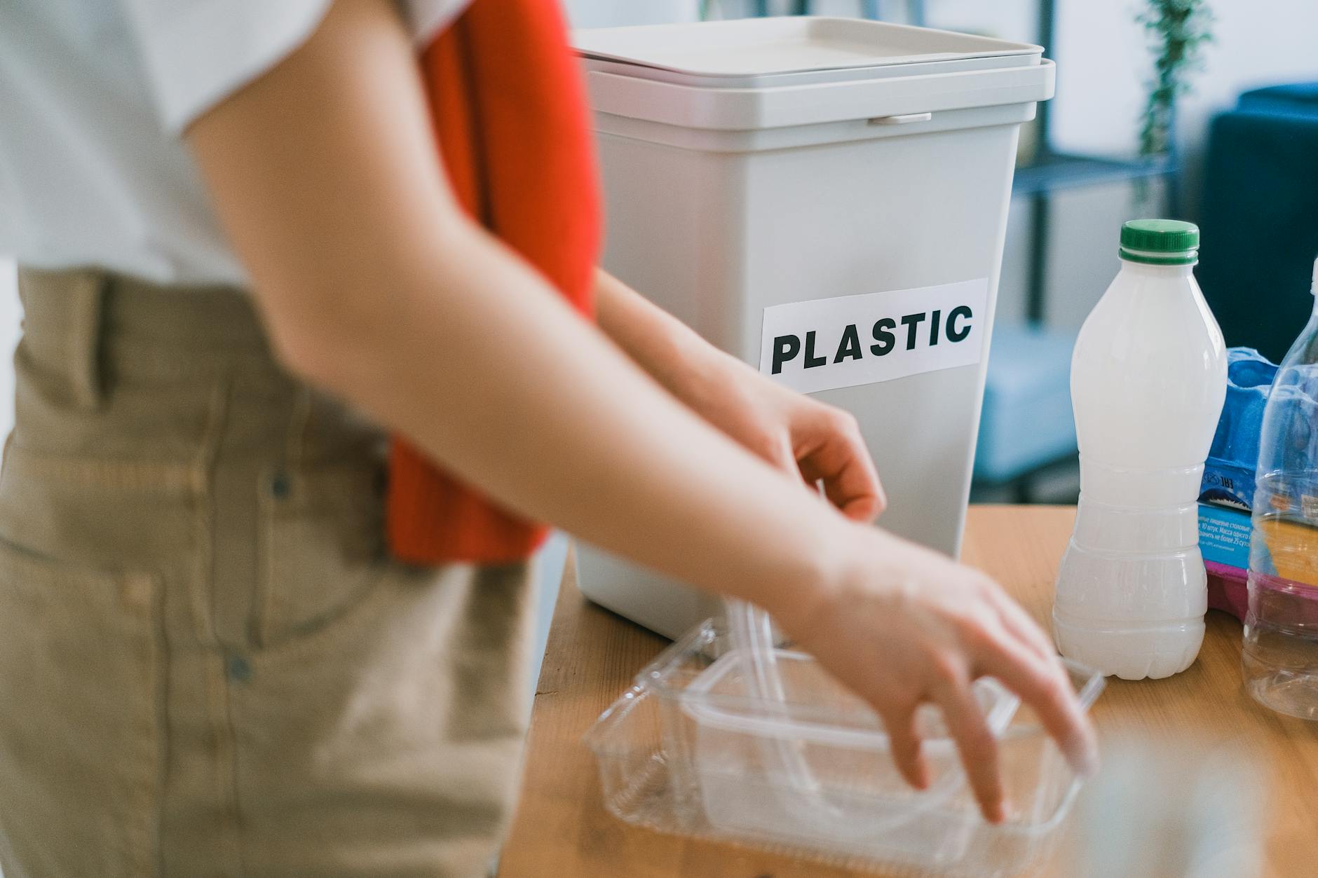 Kobieta w domowej kuchni wrzuca plastikowe odpady do osobnego pojemnika