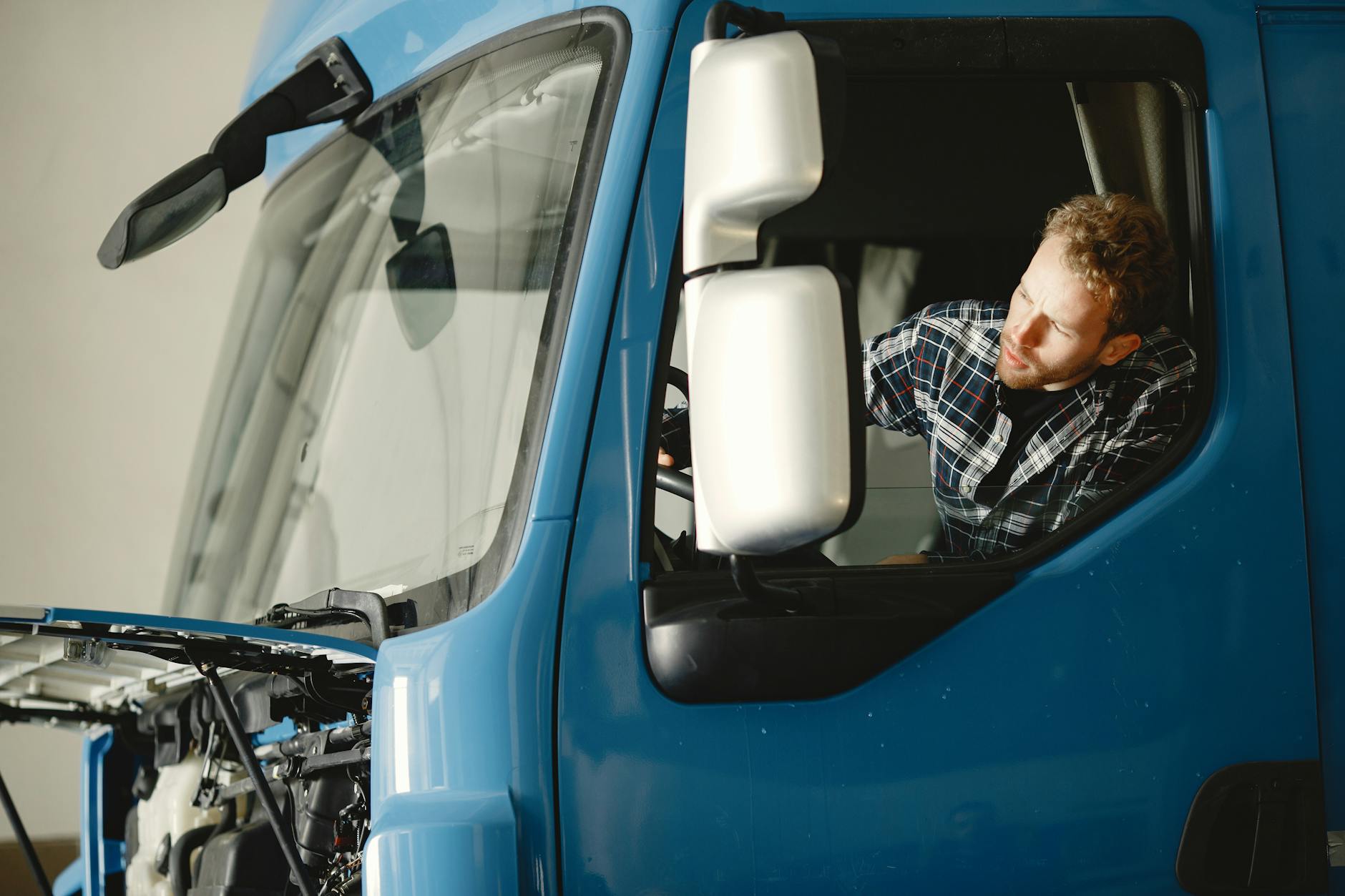 Mechanik sprawdza silnik niebieskiej ciężarówki w hali warsztatowej