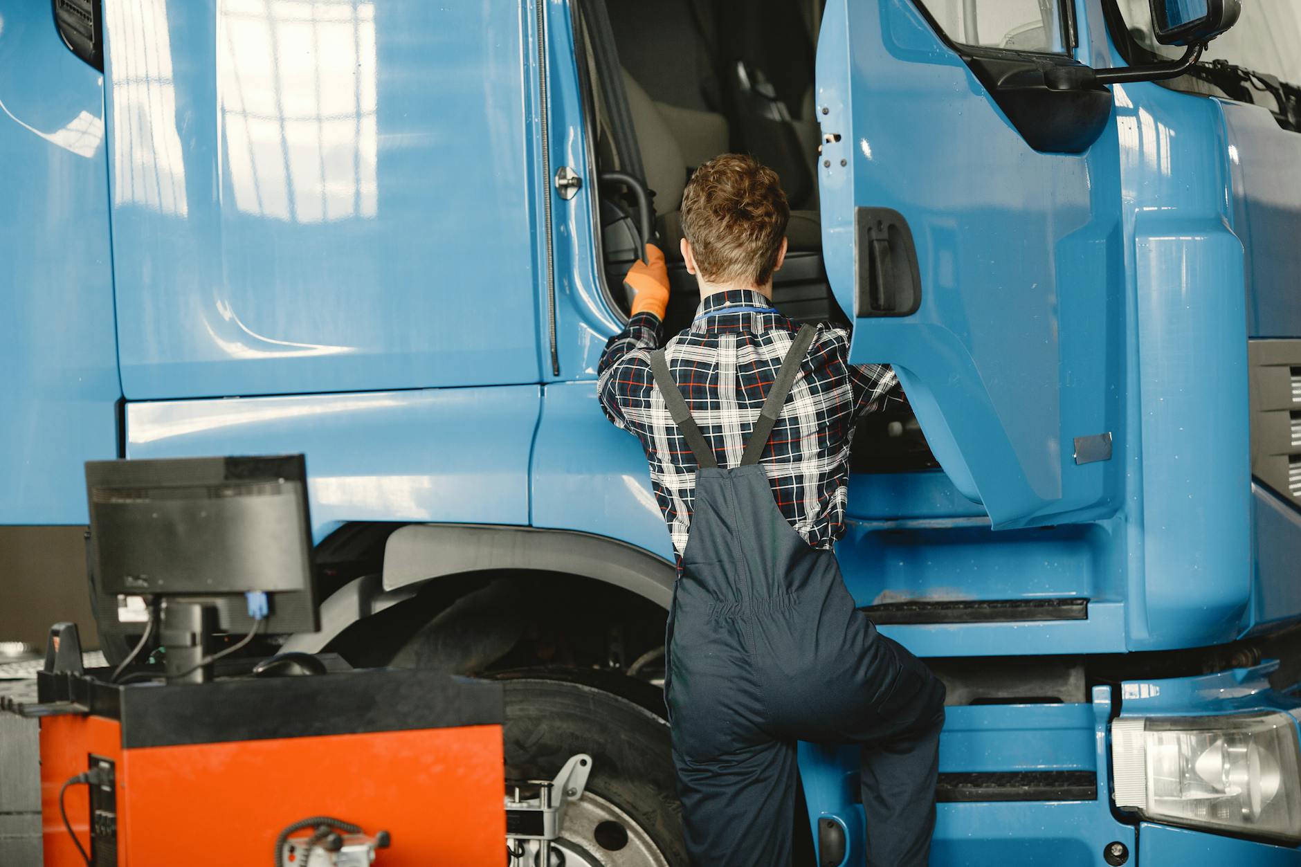 Mechanik w kombinezonie sprawdza ciężarówkę w warsztacie przed kontrolą ADR