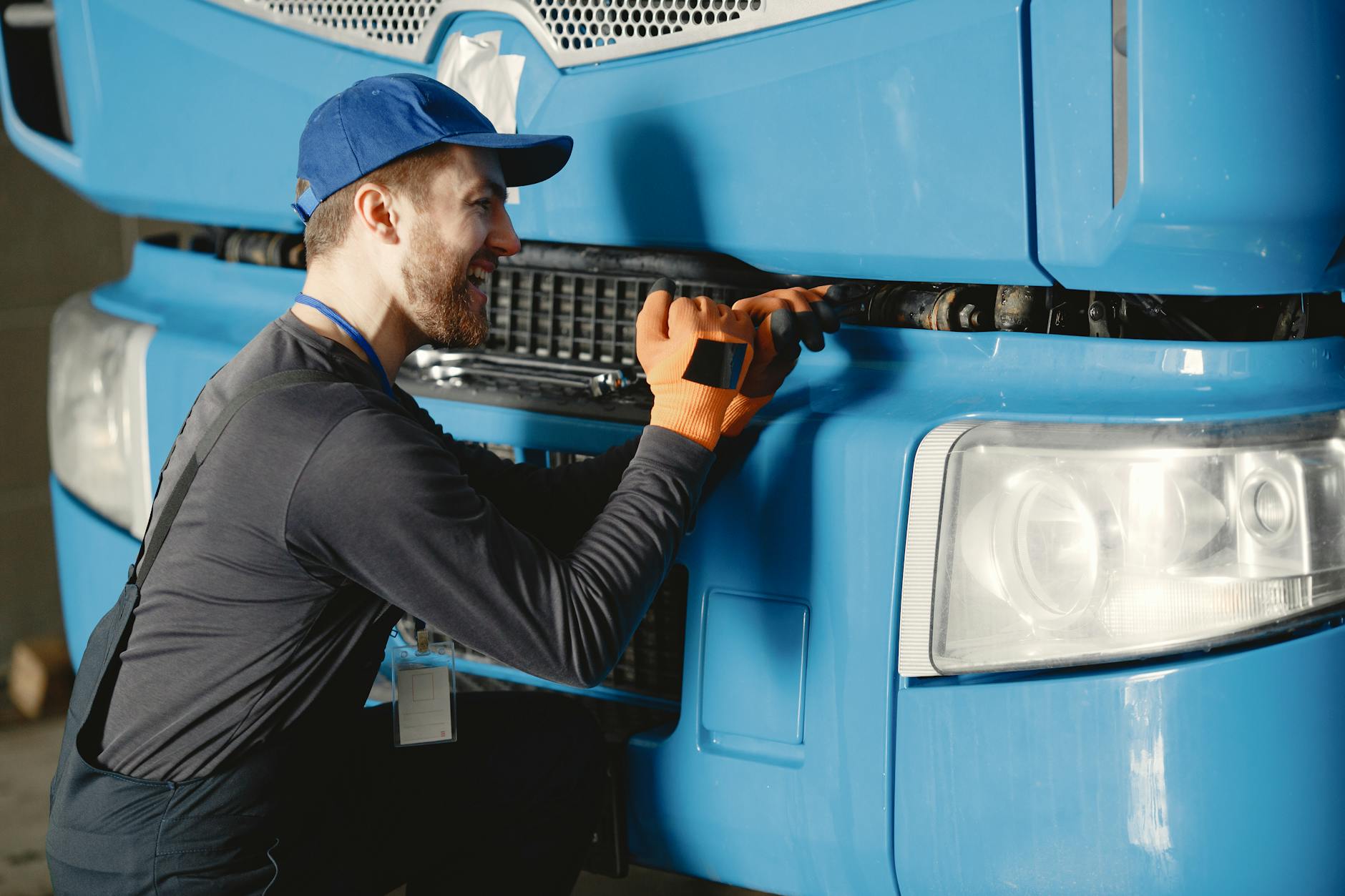 Mechanik w uniformie uśmiecha się podczas przeglądu niebieskiej ciężarówki