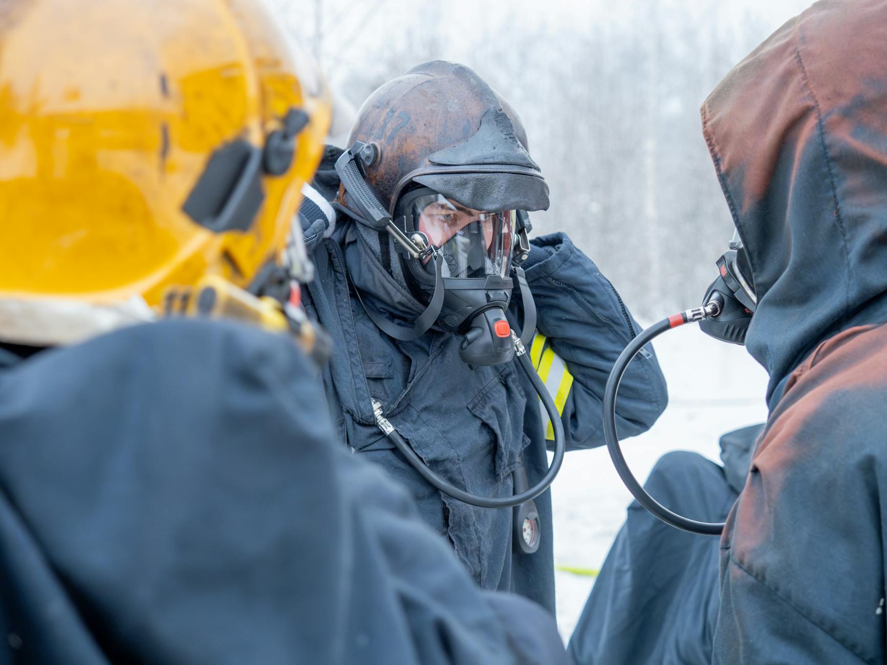 Strażacy w maskach ochronnych rozmawiający w ośnieżonym lesie