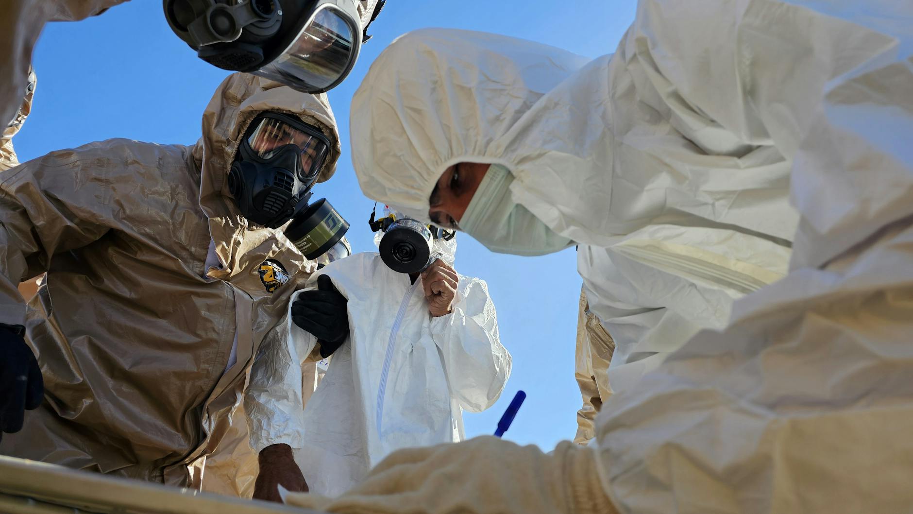 Technicy w kombinezonach chemicznych i maskach gazowych podczas inspekcji