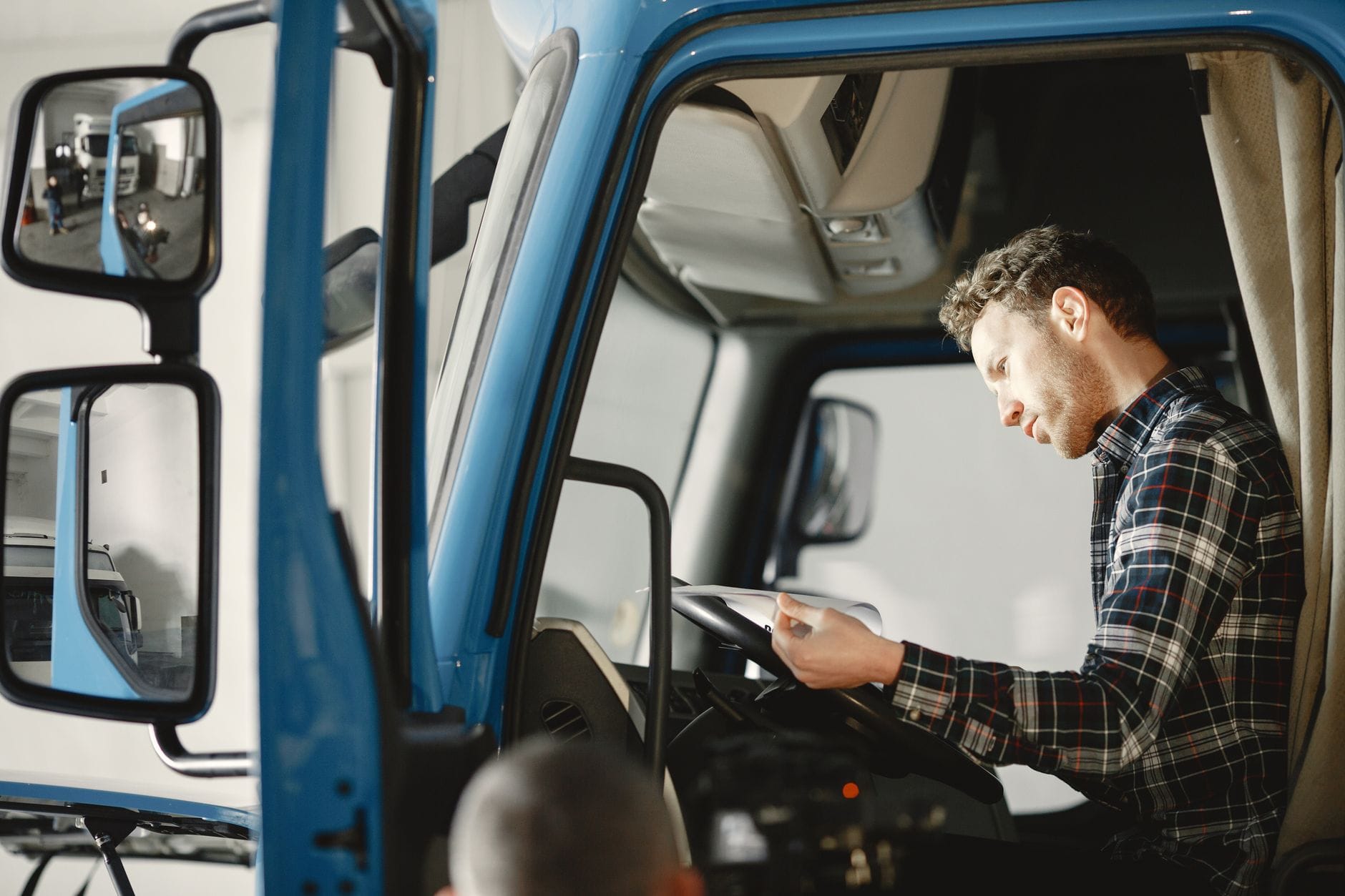 Mechanik w koszuli w kratę sprawdza listę kontrolną w kabinie ciężarówki