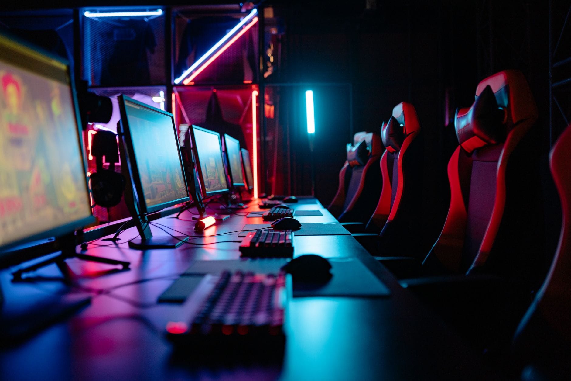 Pokój gamingowy z neonowym oświetleniem, komputerami i fotelami dla graczy