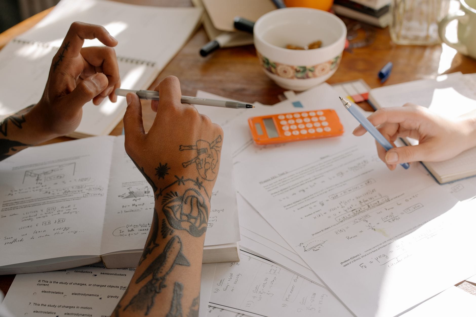 Studenci wspólnie uczą się do egzaminu przy notatkach i kalkulatorze